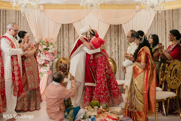jewel toned wedding decor,floral arch backdrop,bride and groom portrait,pastel bridal outfit,groom in sherwani,romantic floral wedding photo,luxury south asian decor,vibrant wedding photography,colorful wedding stage,couple celebration portrait