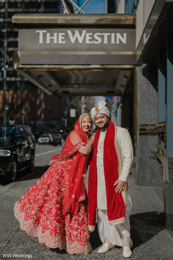 wedding venue exit,the westin wedding photo,red bridal lehenga,ivory groom sherwani,south asian wedding couple,joyful wedding moment,newlyweds walking together,cultural wedding attire,romantic wedding exit,elegant hotel wedding photo