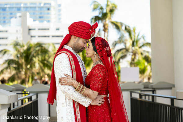 bride and groom hug,red lehenga,wedding attire,candid couple,outdoor romance,joyful embrace,cancun wedding,cultural attire,destination love,sweet moment