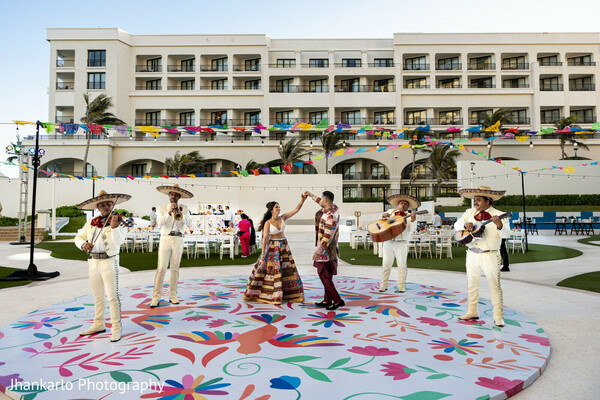 bridal entrance,resort backdrop,traditional dancers,indian wedding procession,cultural performance,cancun wedding,bride in spotlight,festive arrival,outdoor celebration,grand entrance