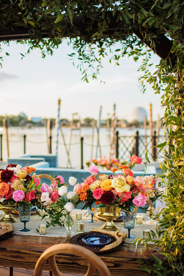 lakeside wedding,floral tablescape,pastel decor,waterfront view,luxury dining,elegant setup,romantic celebration,gold details,destination wedding,modern romance