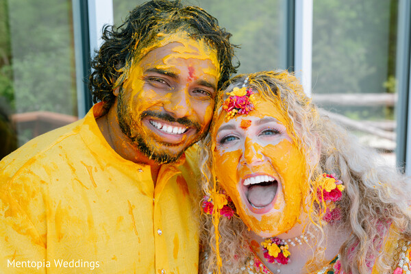 haldi paste,couple laughing,pre-wedding fun,turmeric ceremony,vibrant tradition,candid love,yellow outfits,emotional moments,close-up couple,joyful tradition