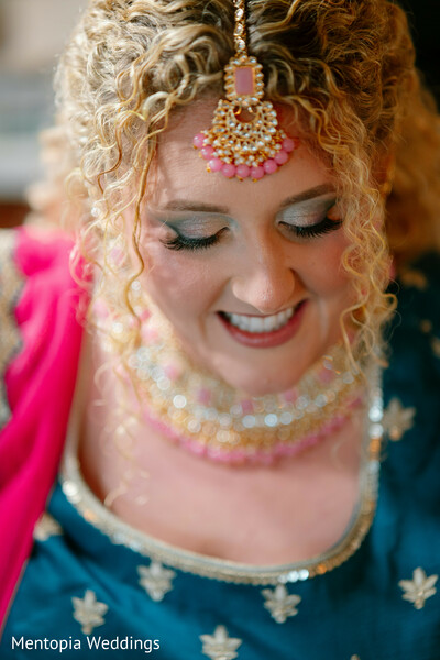 : bridal beauty,close-up smile,south indian braid,floral hair decor,traditional jewelry,pink and gold accessories,bridal portrait,intricate details,wedding glam,curly hair