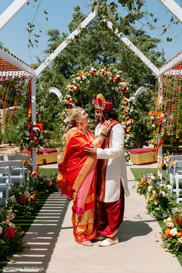 post-ceremony walk,indian couple,traditional attire,bride in red saree,white sherwani groom,wedding exit,floral strands,candid couple,joyful moment,vibrant wedding