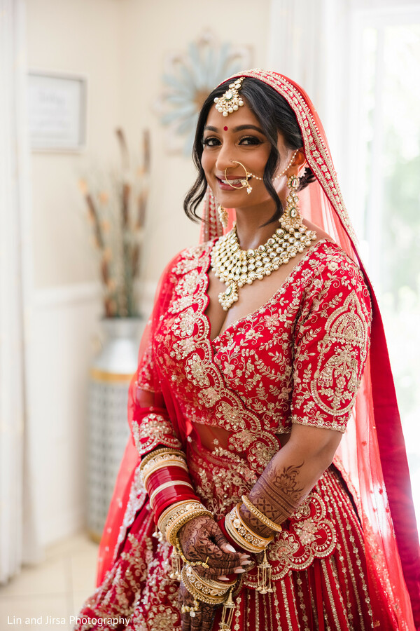 red bridal lehenga,gold embroidery,bridal jewelry,maang tikka,traditional bride,indoor portrait,mehndi hands,south asian beauty,wedding day glow,bridal elegance