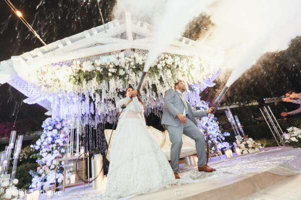wedding celebration,reception stage,newlyweds,grand finale,luxury wedding,white decor,outdoor event,joyful moment,south asian couple