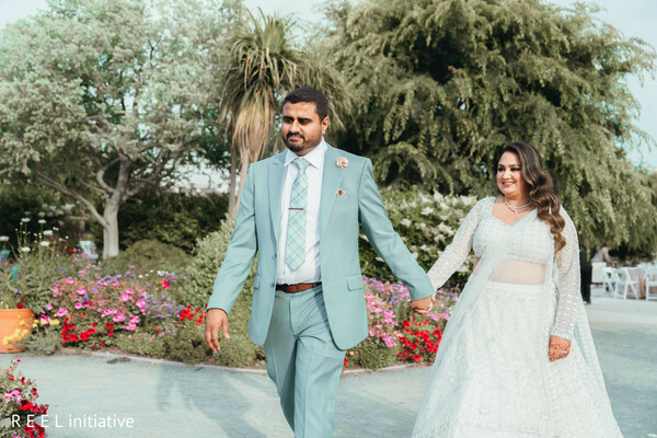 couple portrait,pastel blue outfits,garden walk,outdoor venue,post-ceremony,south asian couple,elegant attire,newlyweds,natural light,romantic moment