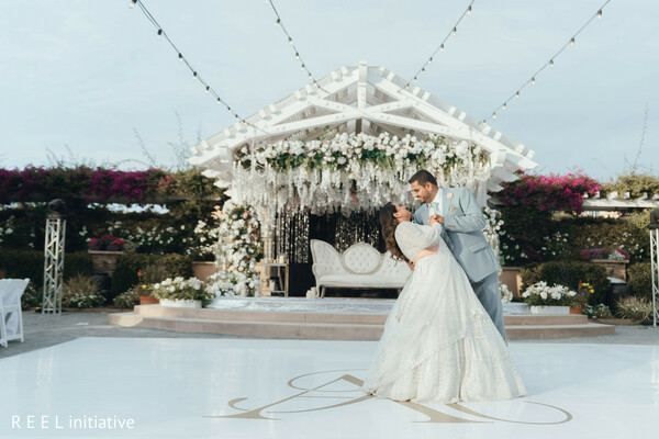 first dance,reception decor,white florals,chandeliers,romantic lighting,newlyweds,elegant ballroom,south asian reception,love in motion,celebration night
