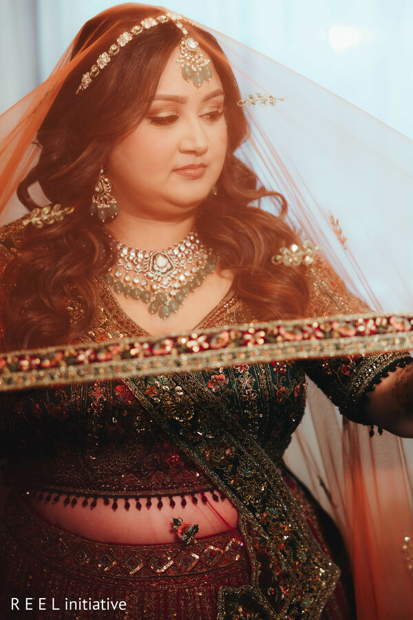 bridal reflection,veil portrait,close-up beauty,red lehenga,jewelry details,soft lighting,emotional bride,south asian wedding,anticipation moment,bridal veil
