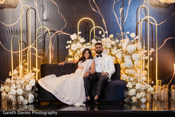 south asian wedding reception,luxury floral backdrop,reception couple portrait,modern indian wedding style,glamorous lehenga,black tie fusion wedding,elegant wedding lounge,evening wedding decor,romantic reception moment,luxury wedding design
