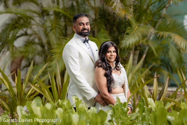 south asian destination wedding,ivory bridal lehenga,modern indian groom attire,tropical wedding portraits,luxury indian wedding couple,intimate wedding poses,palm garden wedding,bridal mehndi details,elegant south asian style,romantic couple portraits