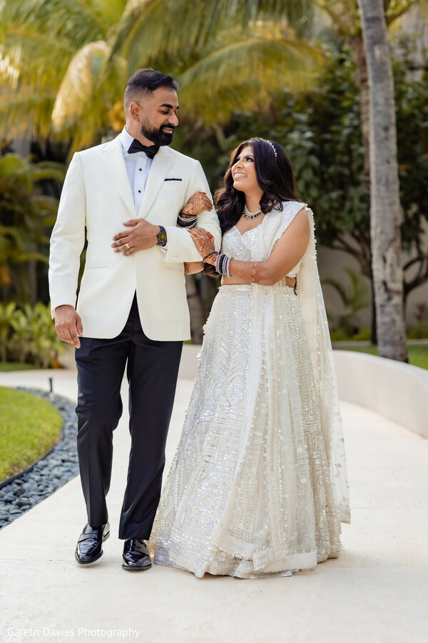 south asian wedding couple,ivory lehenga bride,ivory tuxedo groom,destination wedding portraits,tropical wedding setting,bridal bangles and mehndi,candid wedding moments,luxury indian wedding,pre-ceremony portraits,modern indian wedding style