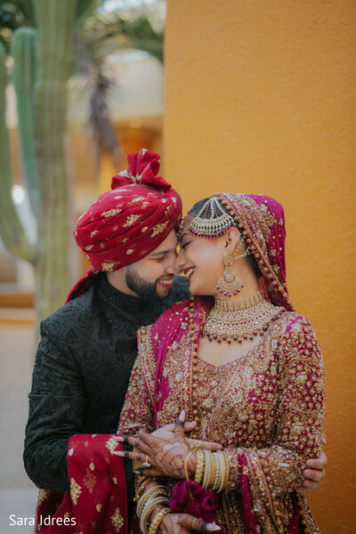 intimate couple portrait,magenta bridal dupatta,embroidered wedding attire,romantic wedding embrace,south asian bride jewelry,groom turban style,emotional wedding moment,cultural wedding fashion,close-up wedding love,candid couple portrait