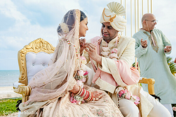 indian wedding ceremony,ring exchange ritual,beach mandap,sacred vows,bridal lehenga,groom sherwani,traditional hindu wedding,emotional moment,cultural symbolism,seaside wedding