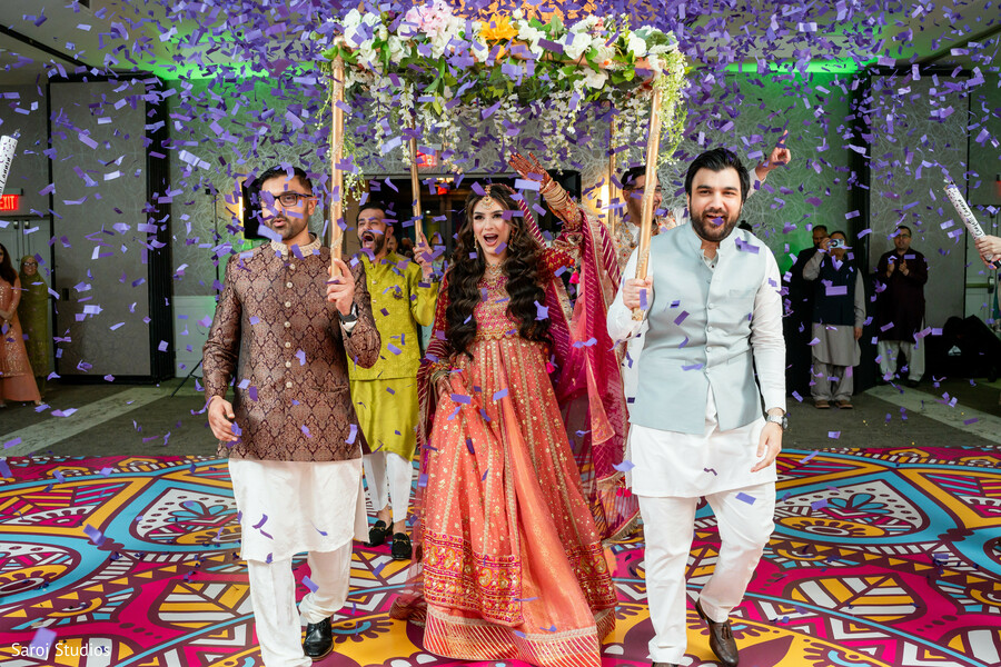 bridal entrance,phoolon ki chadar,wedding celebration,confetti moment,south asian wedding joy,lehenga twirl,ceremonial entrance,festive wedding scene,cultural traditions,joyful bride