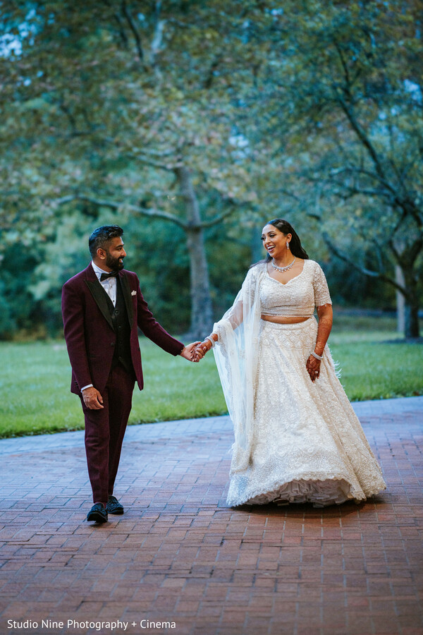 couple walking,outdoor wedding,romantic couple,second wedding look,bridal fashion,groom fashion,wedding attire,serene atmosphere,natural surroundings,joyful couple