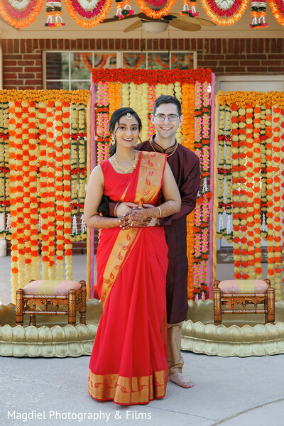 haldi portraits,marigold backdrop,red sari bride,pre wedding couple,indian attire,joyful embrace,cultural celebration,outdoor ceremony decor,south asian love,festive colors