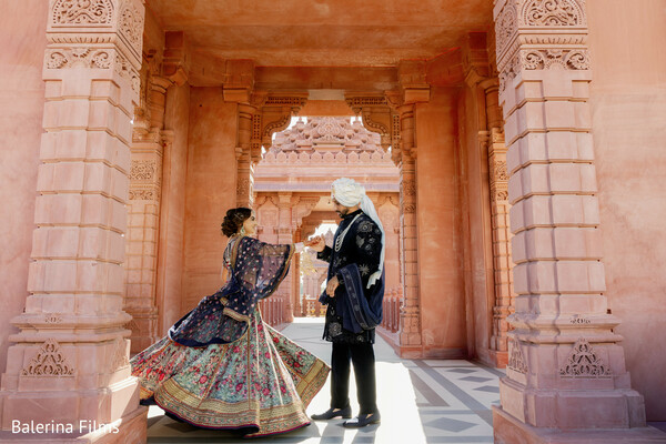 palace architecture wedding,bride twirling lehenga,navy sherwani groom,destination wedding portrait,sandstone arches backdrop,royal indian wedding vibe,heritage venue photography,dramatic bridal spin,cultural wedding elegance,south asian luxury wedding