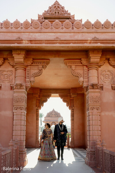 palace architecture wedding,sandstone temple arches,destination indian wedding venue,bride and groom walking,heritage architecture portrait,luxury south asian wedding,royal wedding aesthetic,cultural wedding backdrop,dramatic wedding symmetry,regal couple portrait
