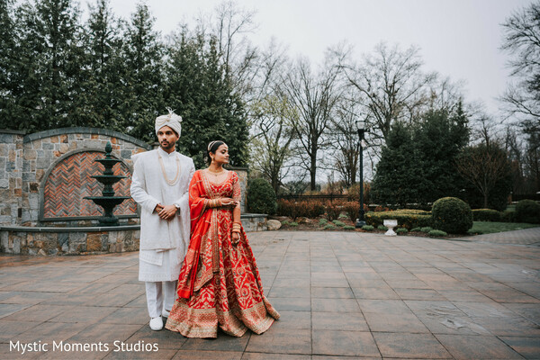 bride and groom portrait,red bridal lehenga,ivory sherwani groom,outdoor courtyard wedding,traditional indian couple,luxury wedding styling,hindu wedding attire,classic couple pose,elegant wedding portrait,cultural wedding fashion