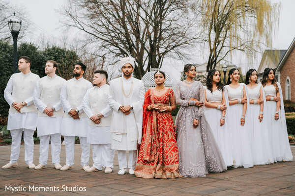 bridal party portrait,coordinated wedding party attire,ivory sherwani groom,red bridal lehenga,bridesmaids in grey,groomsmen in white,south asian wedding party,formal wedding group photo,luxury indian wedding,cultural celebration