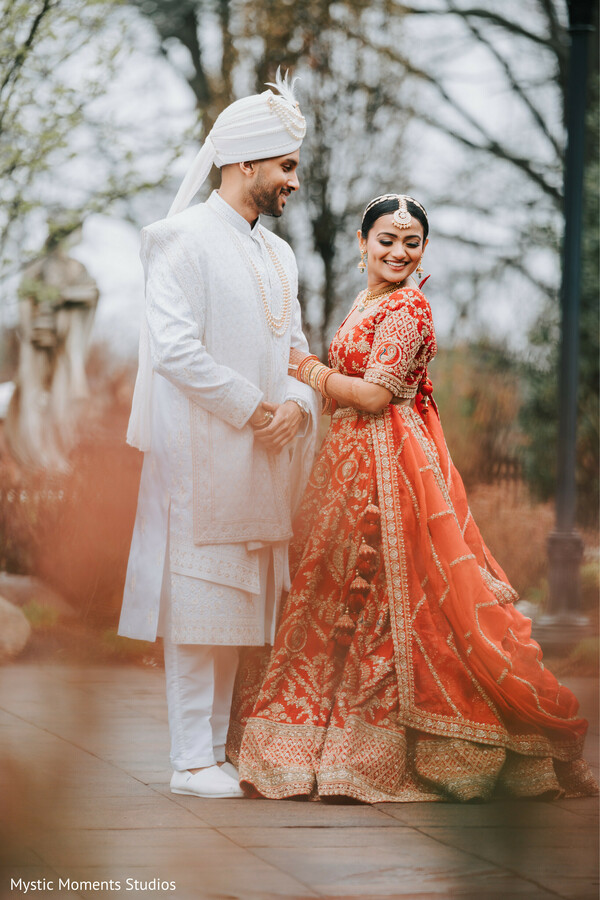 traditional indian couple,red bridal lehenga,ivory sherwani groom,romantic outdoor portrait,hindu wedding attire,bride and groom smile,classic indian wedding,elegant wedding photography,cultural bridal fashion,timeless couple portrait