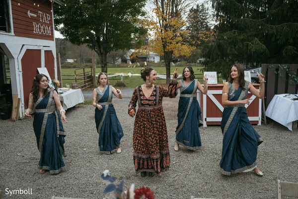 bridesmaids dance performance,teal sari outfits,rustic barn venue,wedding choreography,pre-reception celebration,south asian wedding dance,countryside venue,festive bridal squad,outdoor wedding party,joyful wedding traditions