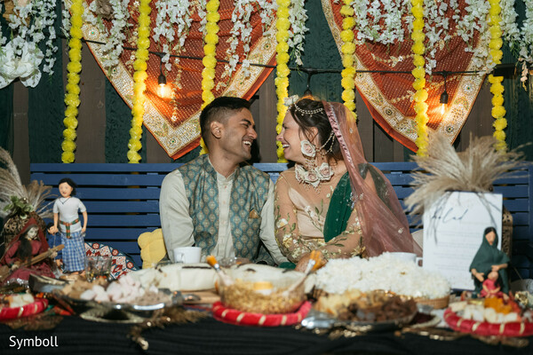 mehndi celebration decor,marigold garlands,floral bridal jewelry,sage green kurta vest,south asian pre-wedding event,festive sweets table,haldi setup,cultural wedding details,candid couple laughter,traditional ceremony backdrop