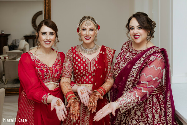 bridal mehndi display,red lehenga choli,maroon saree ensemble,henna ceremony,bridal bangles,south asian bridal squad,gold choker necklace,traditional wedding prep,detailed hand art,cultural bridal moment