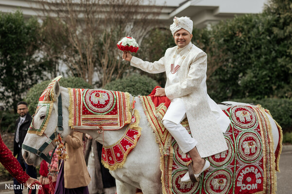 baraat entrance,groom on horse,traditional sherwani,wedding turban,decorated baraat horse,south asian procession,cultural wedding ritual,festive wedding arrival,red and gold embroidery,groom celebration moment