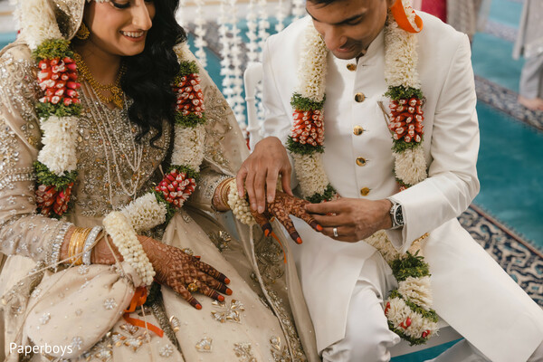 ring exchange moment,bridal mehndi hands,white and red garlands,ivory sherwani groom,champagne bridal outfit,nikah ceremony detail,wedding band placement,intimate wedding ritual,muslim wedding tradition,close-up ceremony portrait