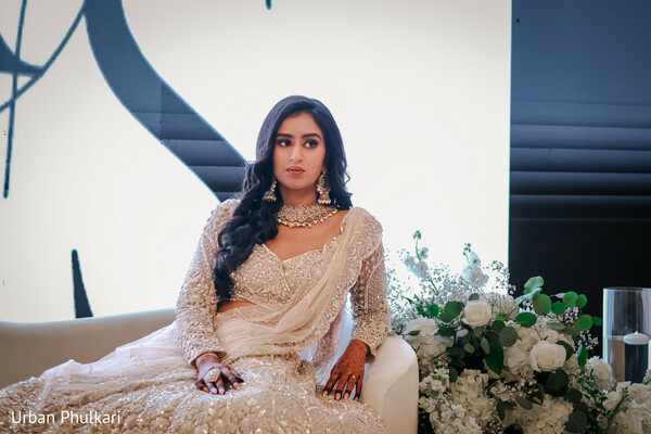 champagne bridal lehenga,statement bridal choker,modern wedding portrait,soft glam bridal look,luxury reception outfit,elegant seated bride,neutral bridal fashion,south asian evening reception,sparkling embroidery detail,contemporary wedding style