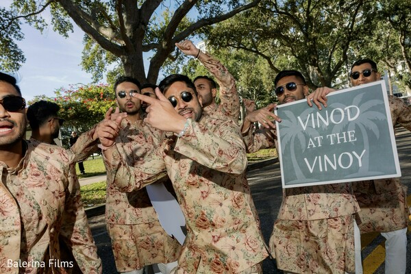 baraat celebration,groom squad photo,floral sherwani outfits,indian wedding procession,fun wedding moment,groom friends dancing,south asian wedding energy,playful wedding sign,outdoor wedding celebration,festive wedding traditions