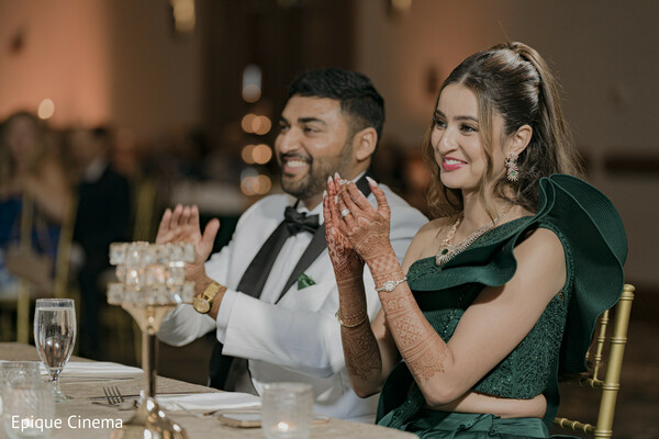 wedding reception candid,couple clapping,guest reactions wedding,indian wedding reception,joyful wedding moment,celebration dinner,bride green dress,groom tuxedo,candid wedding photography,happy couple