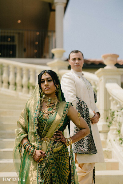 indian bride close up,bridal jewelry details,green saree bride,groom sherwani portrait,powerful couple pose,staircase wedding portrait,traditional indian look,bold bridal styling,wedding fashion details,regal wedding portrait