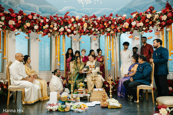 hindu wedding ceremony,floral mandap decor,sacred rituals,priest ceremony,indian wedding traditions,family gathering wedding,red floral canopy,cultural wedding rituals,ceremony seating,traditional wedding setup