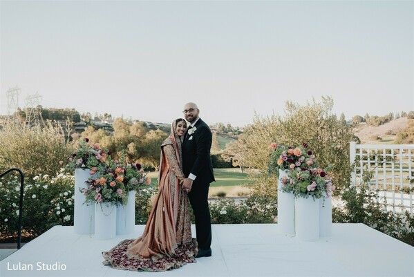 outdoor wedding altar,couple portrait ceremony,floral pedestal decor,bride groom formal portrait,elegant wedding setup,scenic wedding venue,romantic couple pose,ceremony backdrop,wedding florals,classic wedding portrait