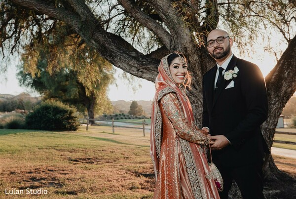 golden hour couple portrait,outdoor wedding photography,bride lehenga details,groom black suit,romantic sunset lighting,nature wedding backdrop,couple smiling portrait,scenic wedding moment,warm light photography,timeless love