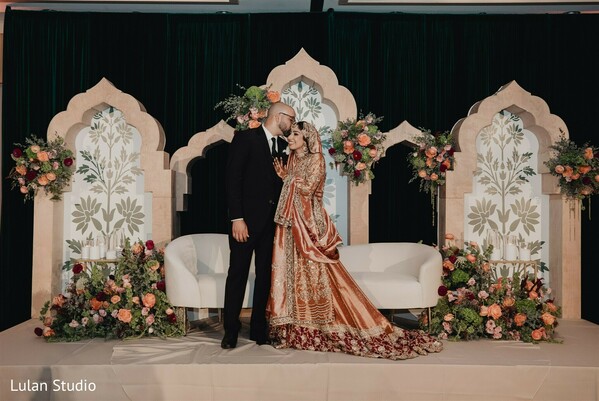wedding stage decor,floral backdrop wedding,indian wedding stage,couple romantic pose,elegant mandap design,bride groom portrait,ceremony stage setup,luxury wedding decor,floral arrangements,intimate wedding moment