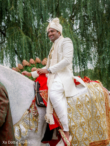 baraat entrance,groom on horse,indian wedding procession,groom sherwani white,traditional baraat,wedding celebration,cultural wedding ritual,horse decor wedding,groom arrival,festive wedding moment