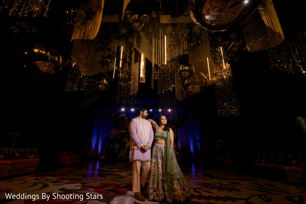 dramatic reception decor,hanging installations wedding,moody lighting portrait,couple evening portrait,luxury wedding ambiance,indian wedding couple,stage lighting decor,romantic pose,grand reception design,artistic wedding photography