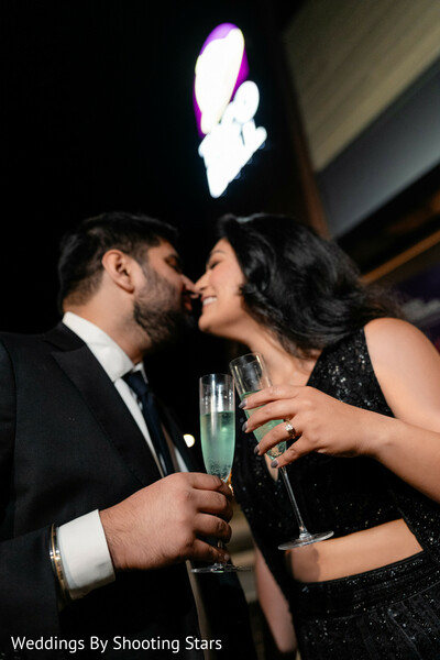 champagne toast couple,romantic night portrait,couple kiss candid,reception night vibes,bride black outfit,groom suit black,intimate moment,nightlife wedding,love celebration,modern romance