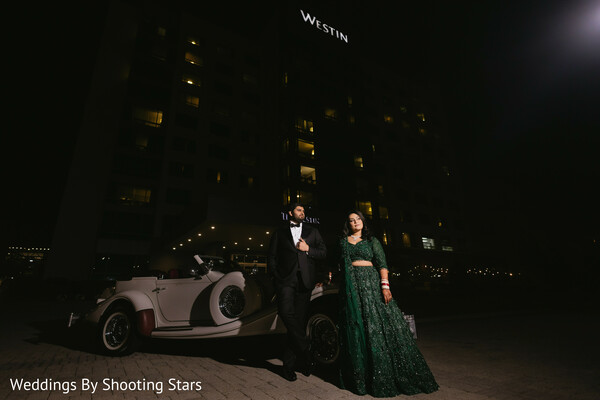 night couple portrait,vintage car wedding,luxury wedding vibe,bride green lehenga,groom tuxedo,hotel exterior wedding,dramatic lighting,stylish entrance,modern indian wedding,elegant couple