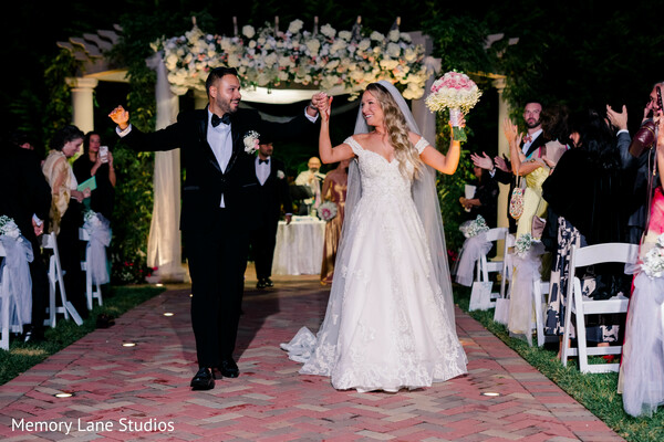 just married couple,ceremony exit celebration,bride white gown,groom tuxedo,wedding aisle walk,guests cheering,joyful wedding moment,newlywed celebration,outdoor ceremony exit,candid happiness