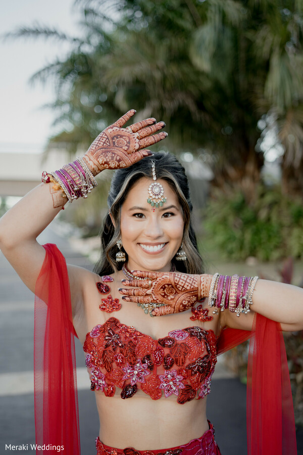 bridal mehndi hands,red lehenga blouse,bride portrait smiling,bridal jewelry maang tikka,colorful bangles stack,destination wedding bride,playful bridal pose,intricate henna design,indian bridal fashion,tropical wedding setting