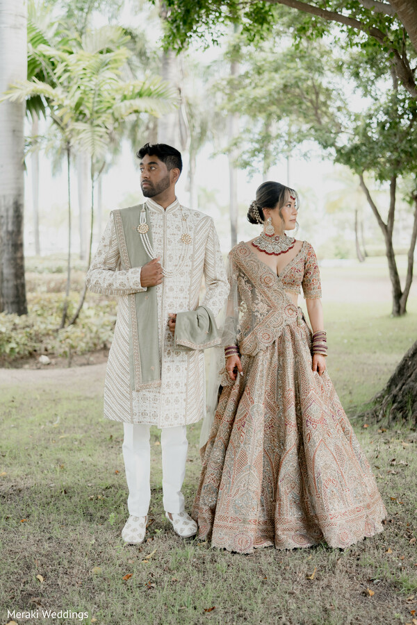 couple portrait outdoors,bridal lehenga embroidery,groom sherwani styling,nature wedding backdrop,romantic couple pose,indian wedding fashion,garden wedding portrait,elegant bridal look,groom formal pose,soft natural light