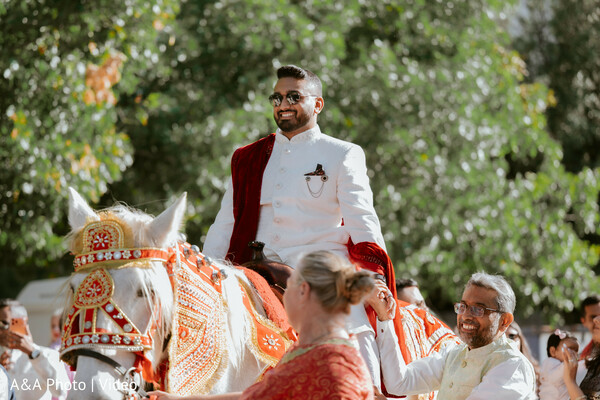 baraat entrance groom,groom on horse,indian wedding procession,groom white sherwani,traditional baraat moment,wedding celebration outdoors,groom arrival ceremony,festive crowd moment,cultural wedding ritual,horse baraat