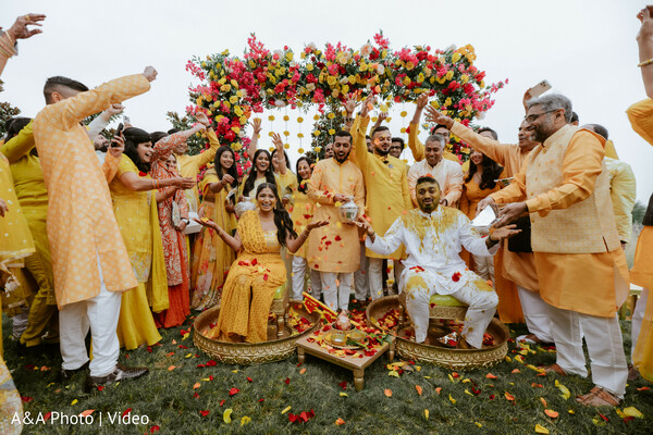 haldi ceremony celebration,flower shower moment,yellow wedding outfits,bride groom seated ritual,floral canopy decor,indian pre wedding ritual,family celebration candid,colorful wedding event,haldi traditions,joyful wedding crowd