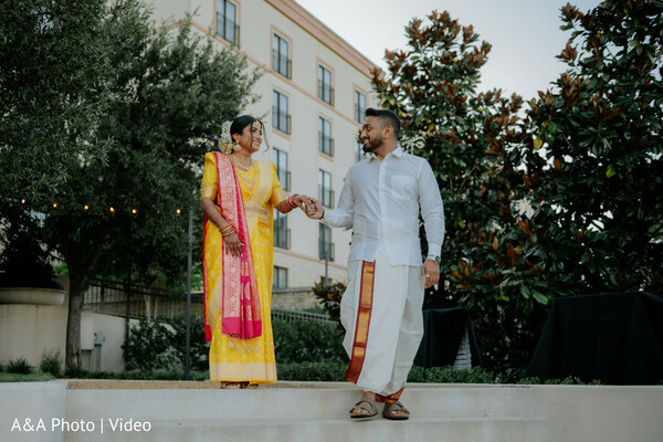 south indian couple portrait,bride yellow saree,groom dhoti outfit,couple holding hands,traditional attire moment,outdoor wedding portrait,cultural wedding fashion,candid couple walk,indian wedding style,romantic stroll