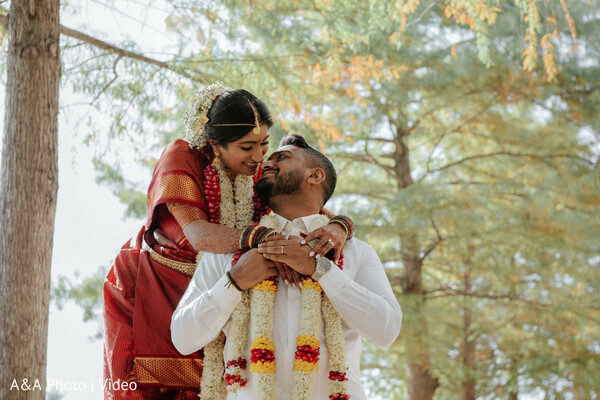 playful couple moment,bride hugging groom,candid wedding portrait,outdoor couple laughter,indian wedding garlands,joyful bride expression,romantic candid shot,natural backdrop couple,love filled moment,wedding day happiness